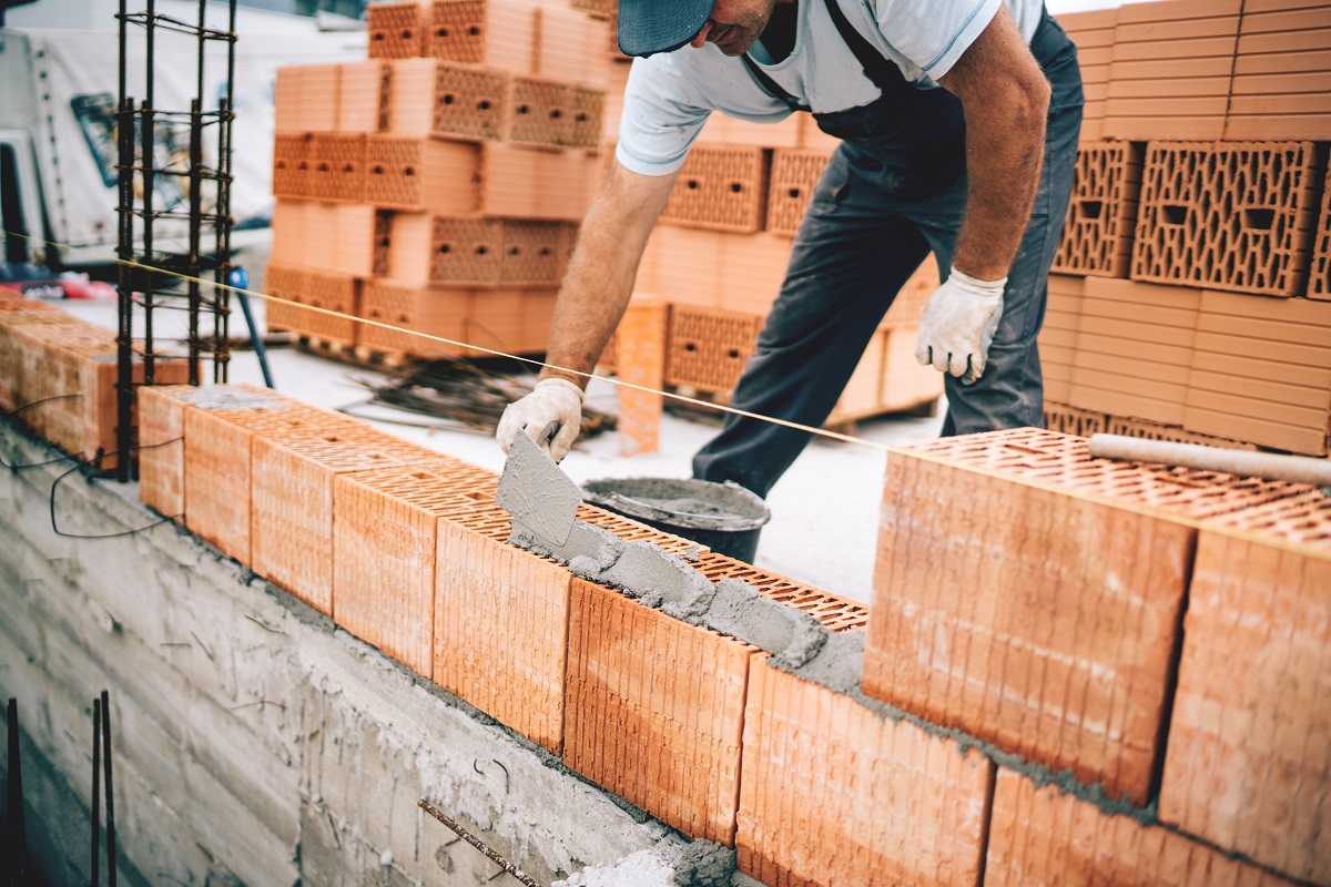 Bricklayer in London laying bricks and checking levels